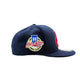 A navy blue Brooklyn Bodega Association x New Era 59FIFTY baseball cap with a circular embroidered front patch and a red white & blue embroidered side logo, shown on a light gray background.